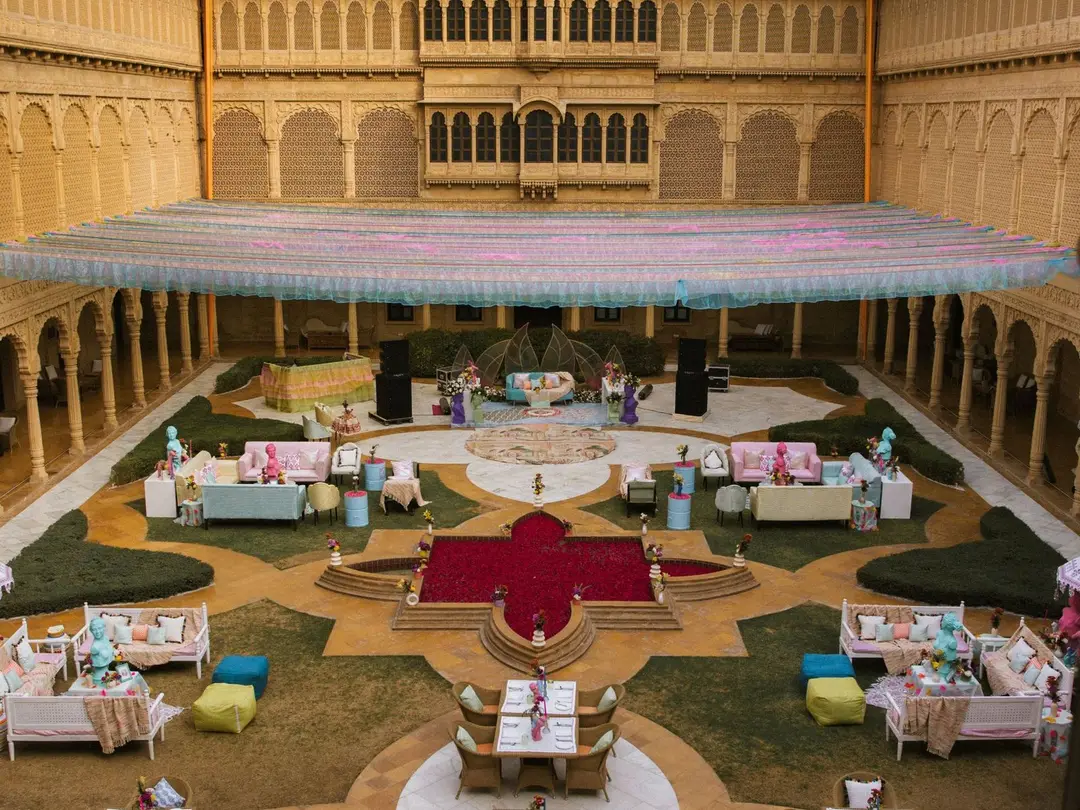 The same courtyard dressed for a wedding: a pastel canopy, lounges, dining tables and a fountain filled with rose petals